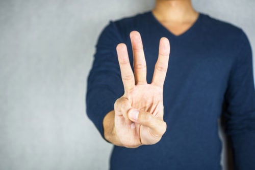 Man holding up three fingers